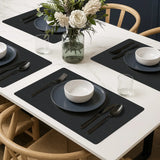 Rechthoekige vinyl placemats van kunststof in zwart ribbelstructuur op moderne eettafel