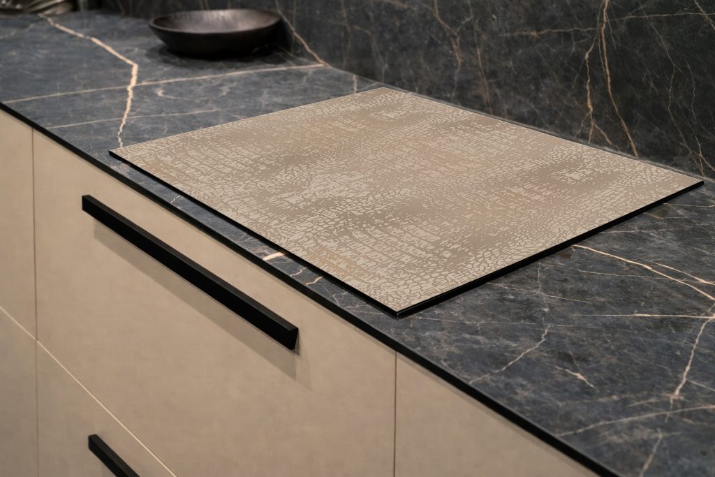 Inductiebeschermer met een zachte taupekleurige organische textuur.